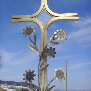 Metallkreuz mit Sonnenblumenverzierung und eingefasstem Glas